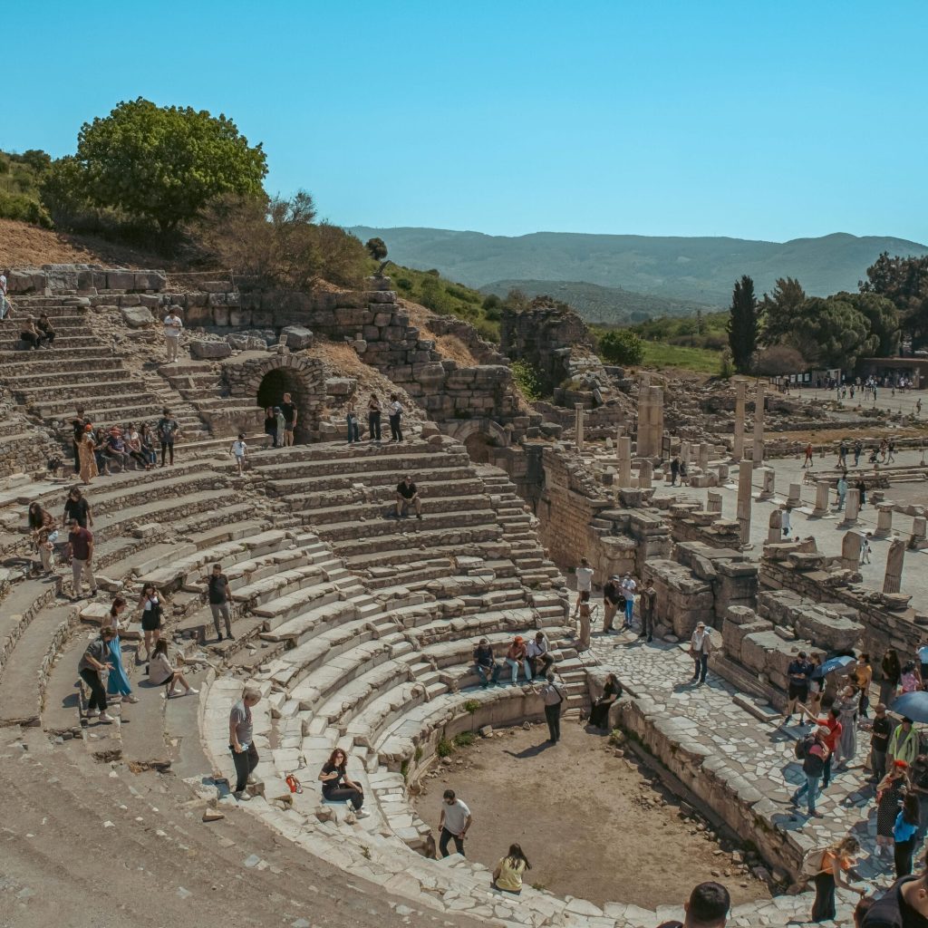 Visitors explore the historic amphitheater ruins in Ephesus, Turkey, on a sunny day.