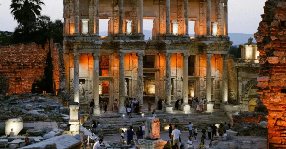 pexels-photo-28000979-28000979 Illuminated Library of Celsus in Ephesus at sunset with tourists exploring the ancient ruins.