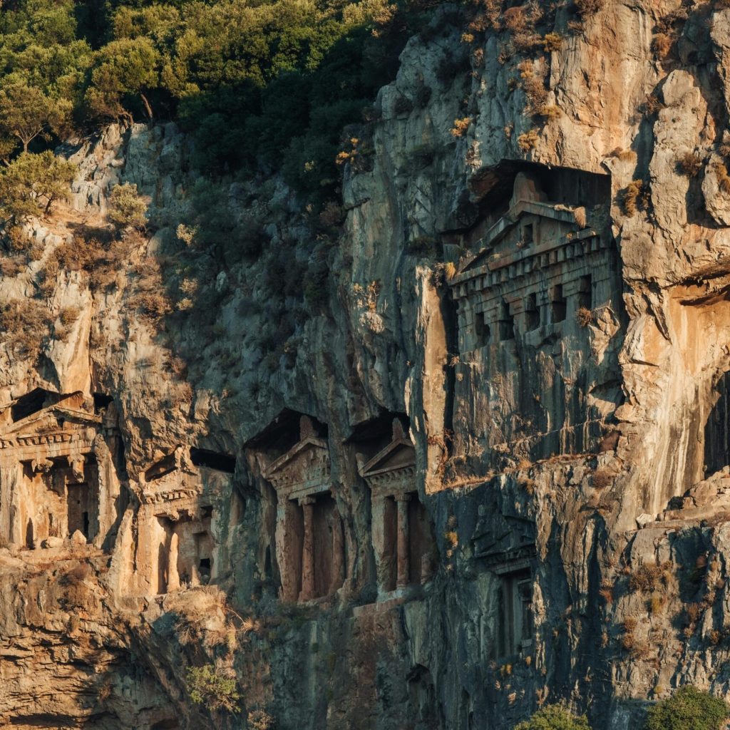 Aerial view of ancient rock-cut tombs carved into a cliff in Dalyan, a popular tourist site in Türkiye.